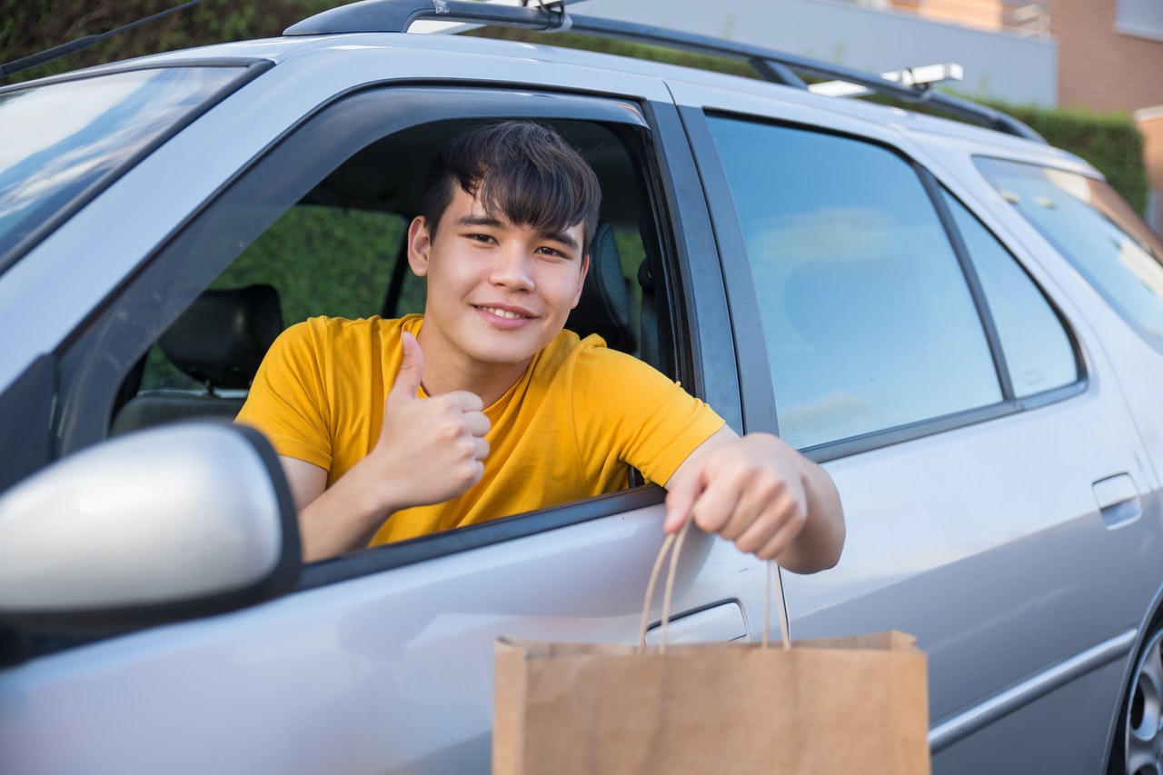Hombre en su auto con bolsa de papel
